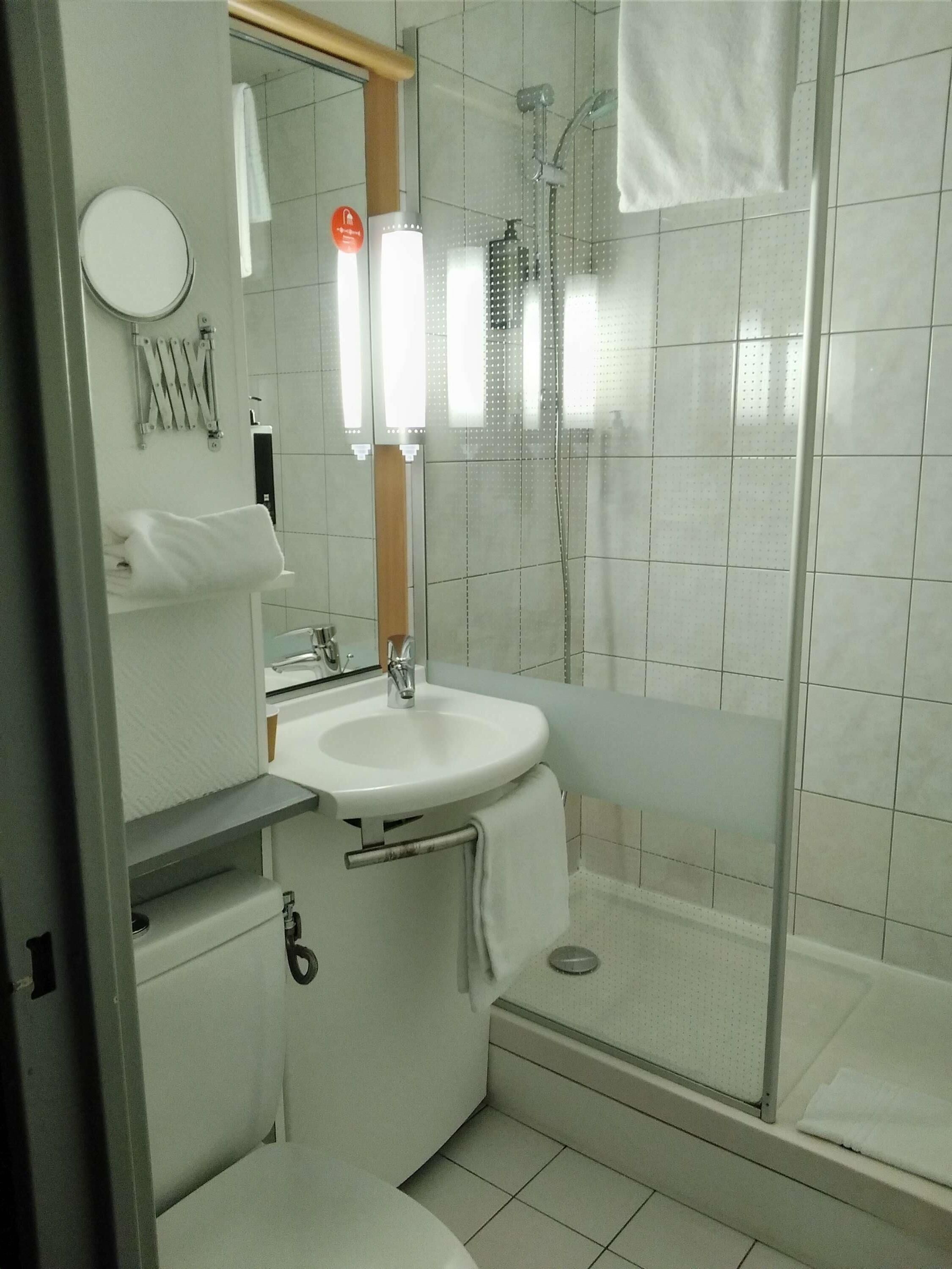 A modern bathroom with a glass-enclosed shower, a white sink, and a mirror.