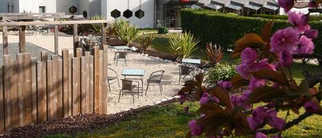 An ibis hotel with a modern architectural design, outdoor seating area, and a well-maintained garden.