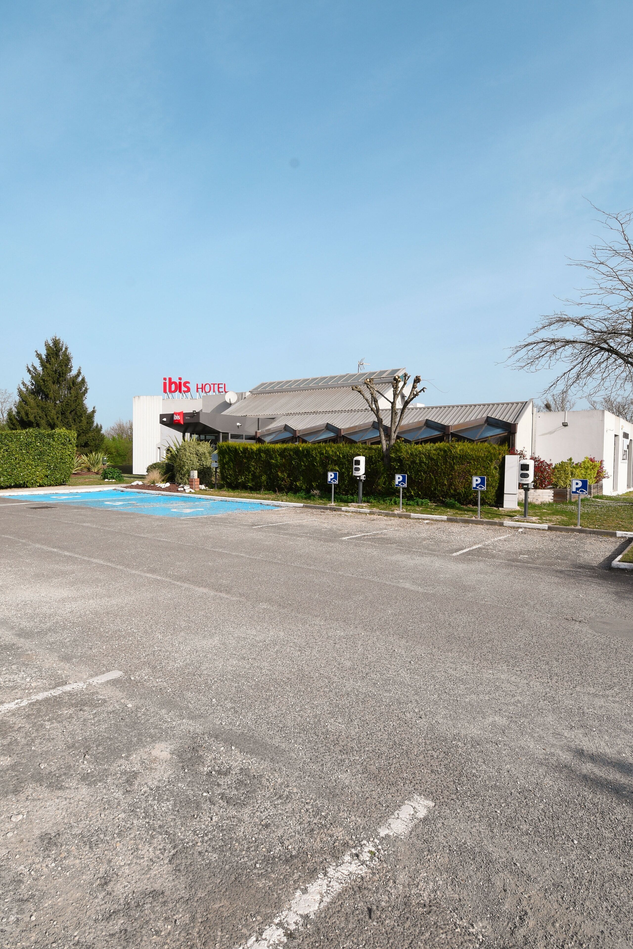 Un estacionamiento frente a un hotel ibis con piscina.