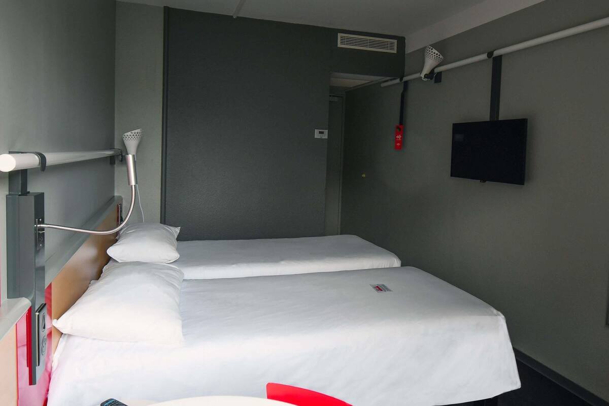 Ein Hotelzimmer mit Bett, Wandfernseher und Deckenventil.
