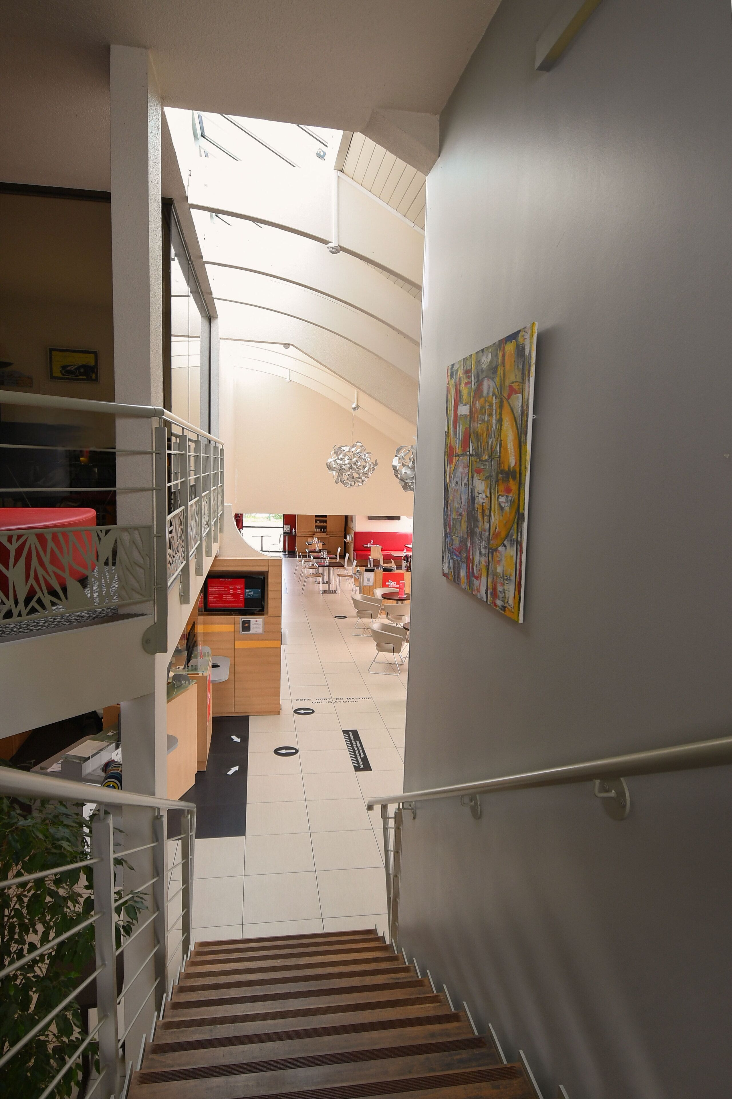 A staircase leading to a dining area with a high ceiling and a painting on the wall.