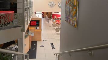 A staircase leading to a dining area with a high ceiling and a painting on the wall.