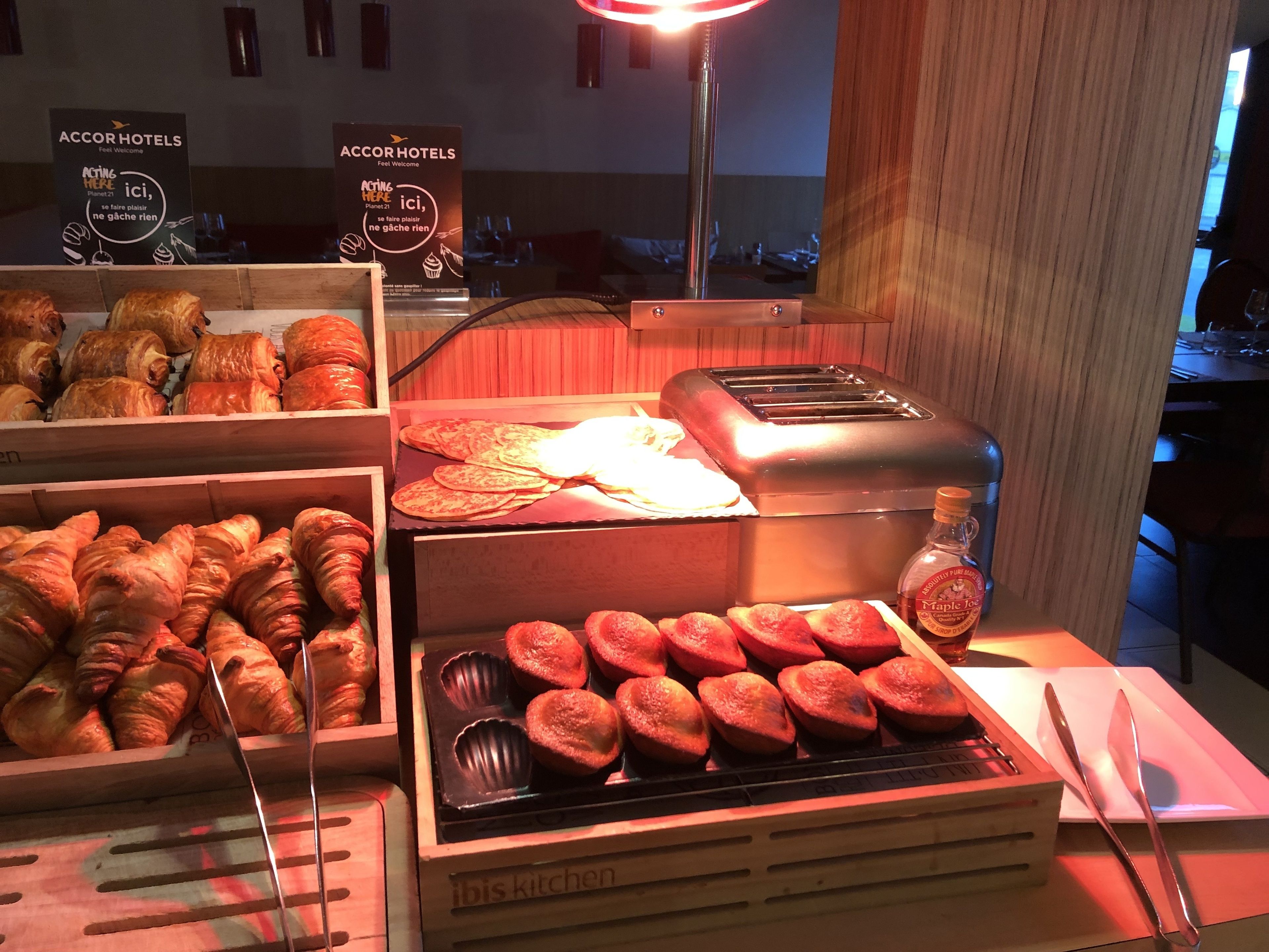 A breakfast buffet with croissants, muffins, and a toaster.