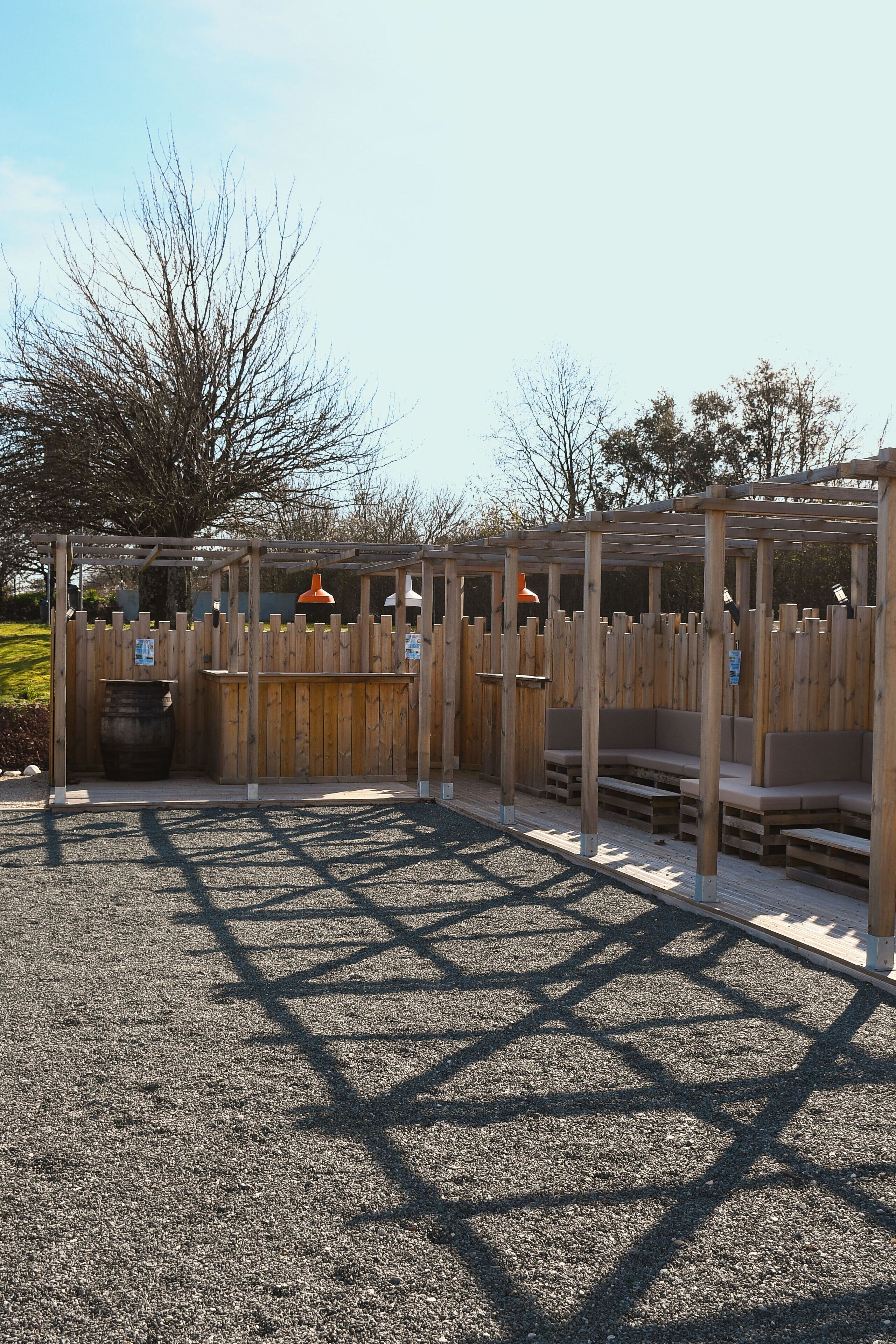 A wooden outdoor seating area with benches and tables, surrounded by a wooden fence.