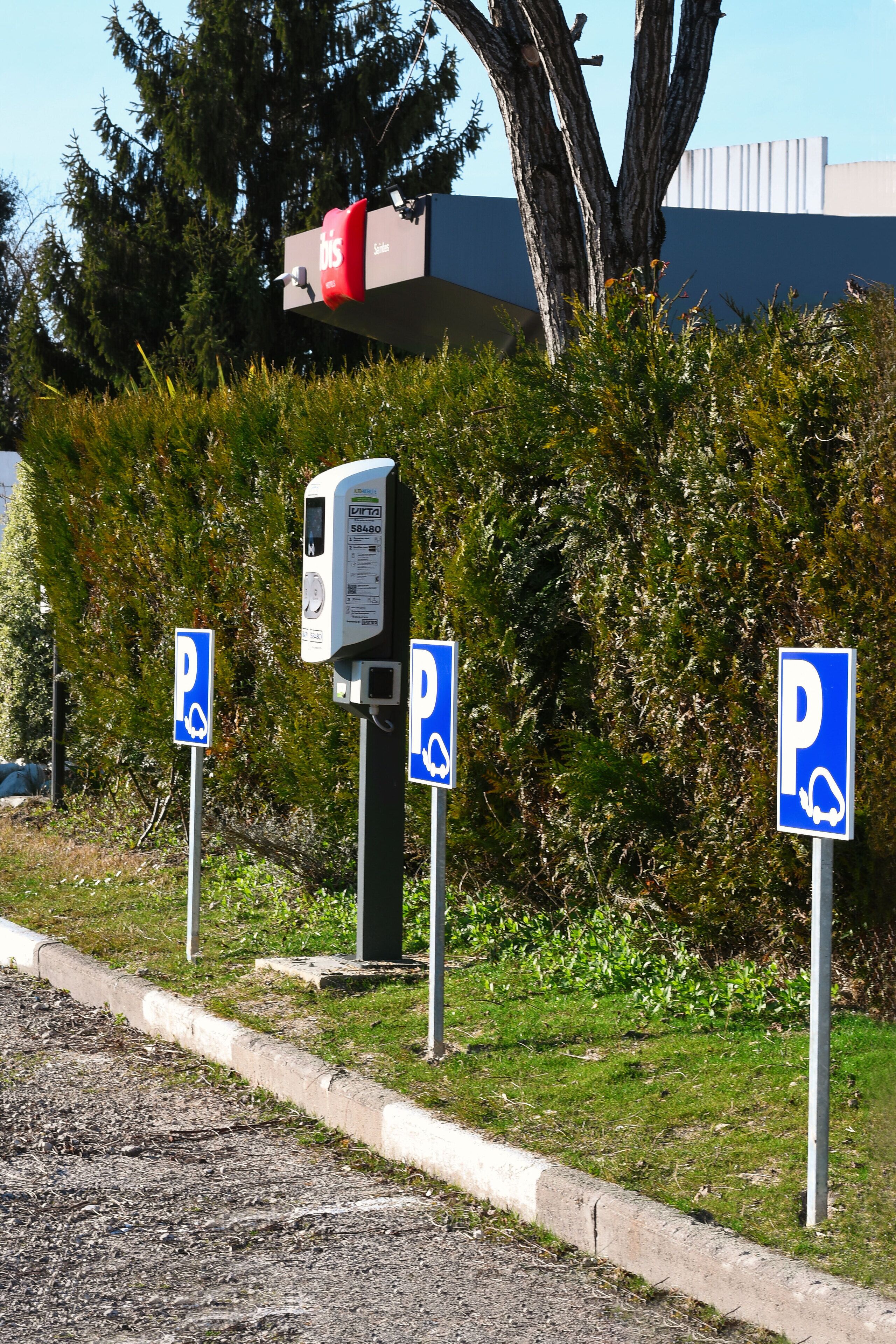 A parking area with a payment kiosk and multiple parking signs.