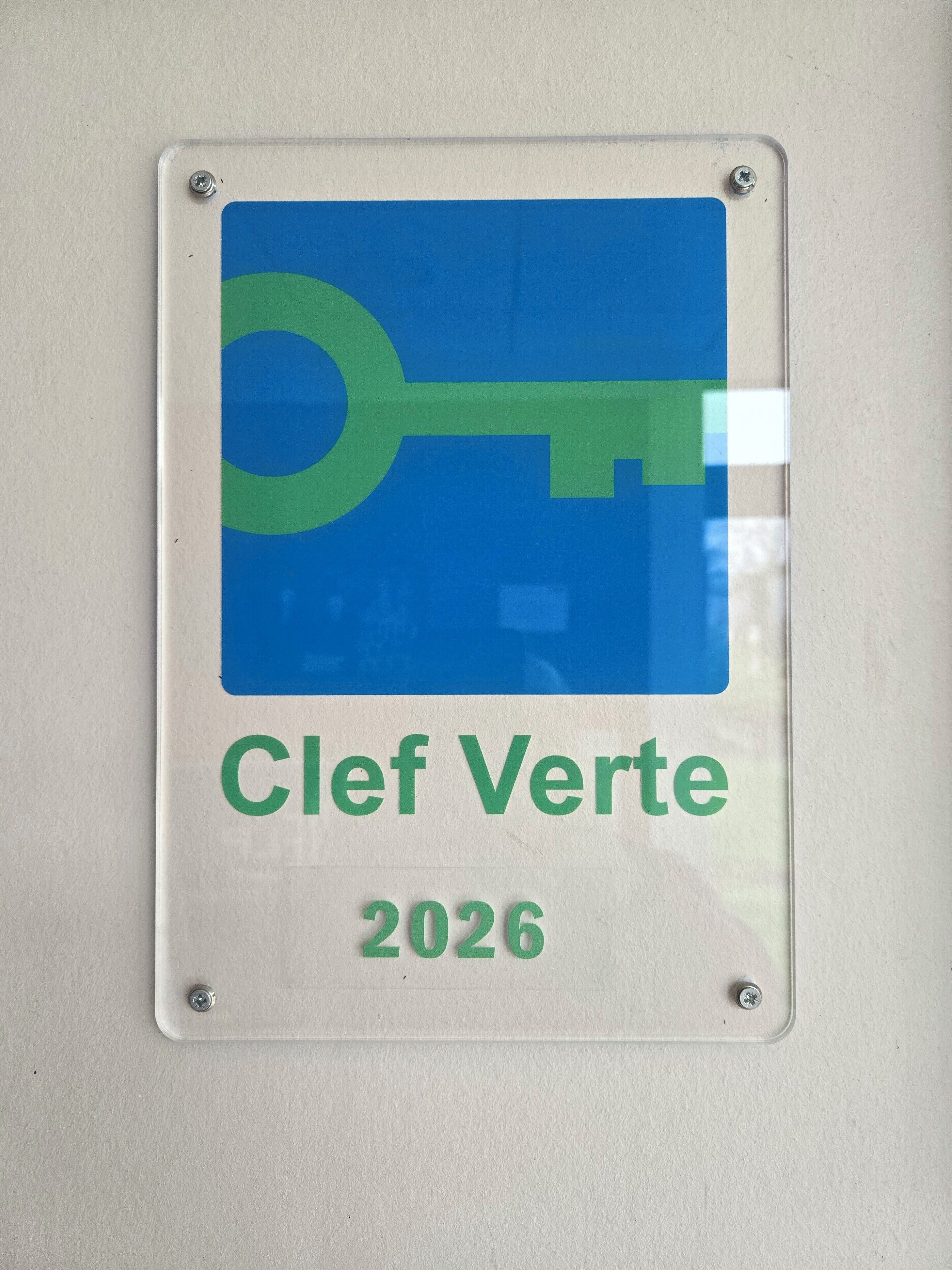 Un letrero con un símbolo de llave y el texto 'Clef Verte 2026' en una pared.