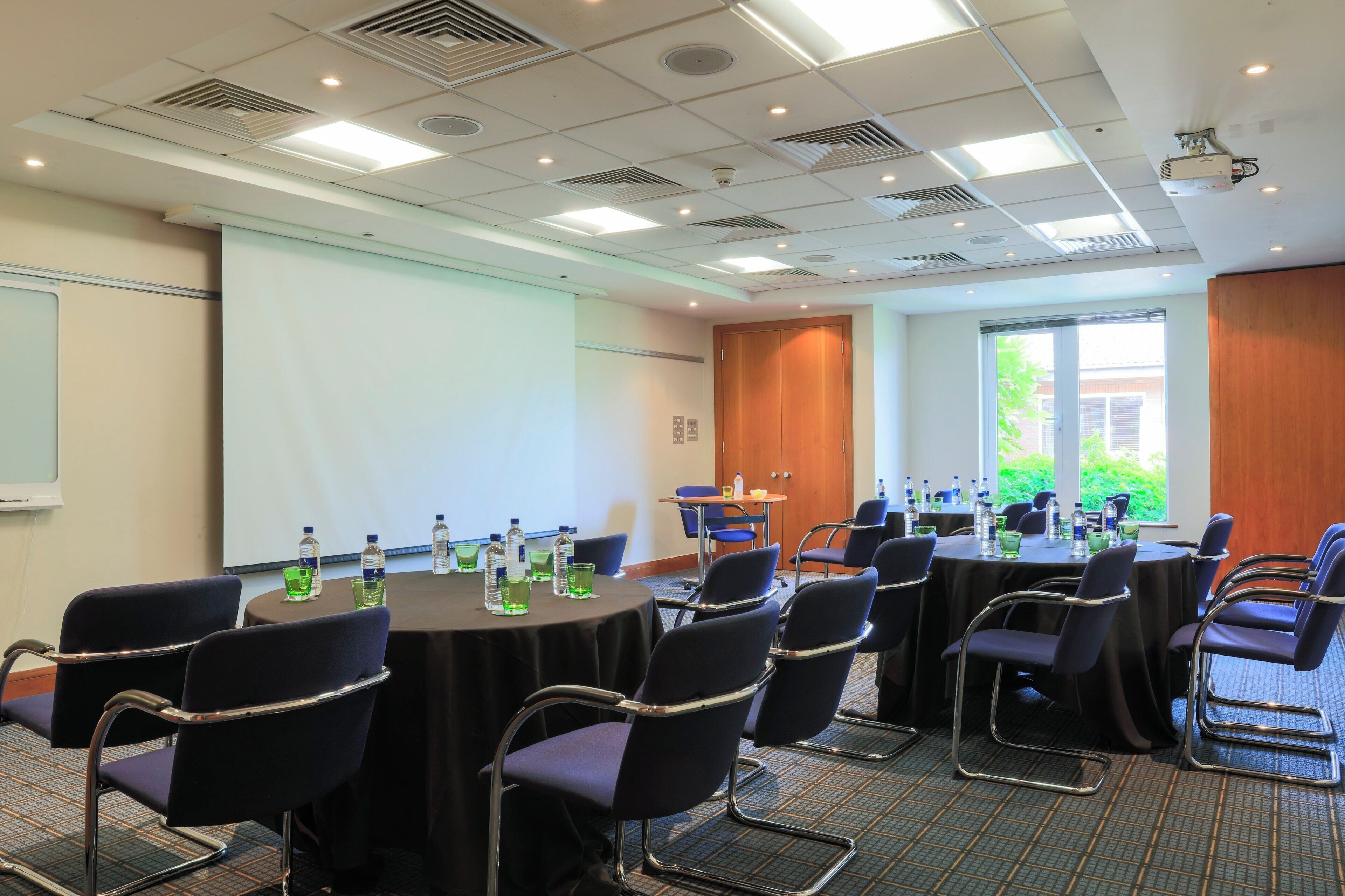 A conference room with round tables, chairs, and water bottles.