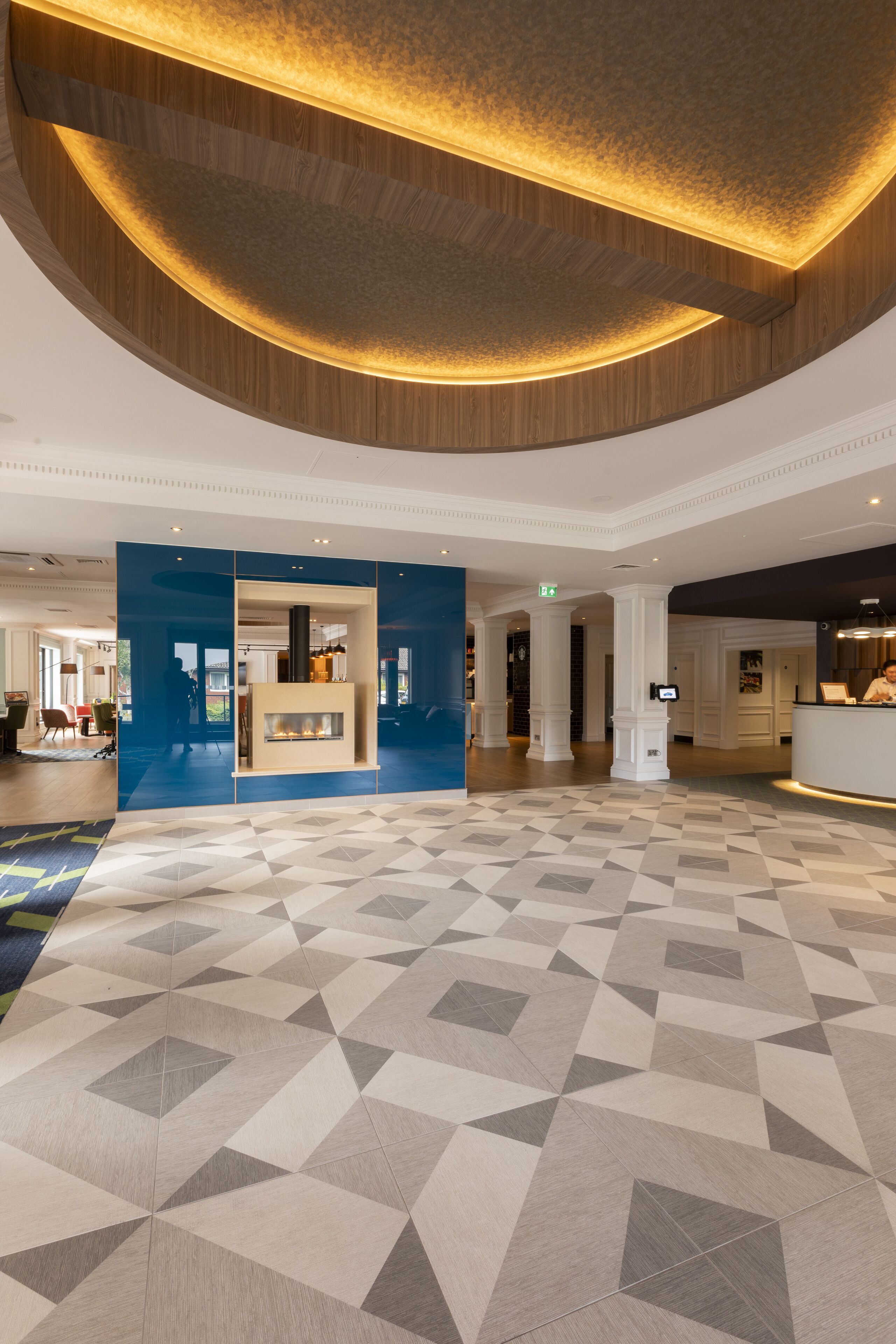 A spacious lobby with a checkered floor, a reception desk, and a fireplace.
