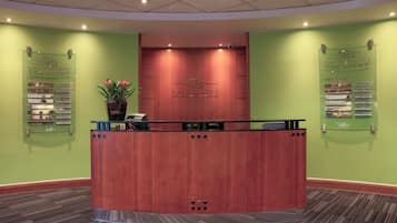 A reception desk with a wooden finish, a potted plant, and a sign listing conference and banquet suites.