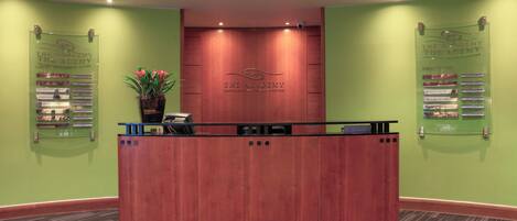 A reception desk with a wooden finish, a potted plant, and a sign listing conference and banquet suites.