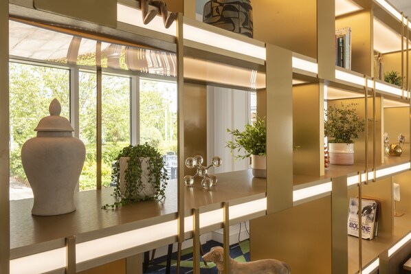 A modern interior with a wooden desk, a potted plant, and a decorative item. - Holiday Inn Guildford by IHG (Guildford)