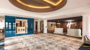A spacious lobby with a geometric patterned floor, a reception desk, and a fireplace.