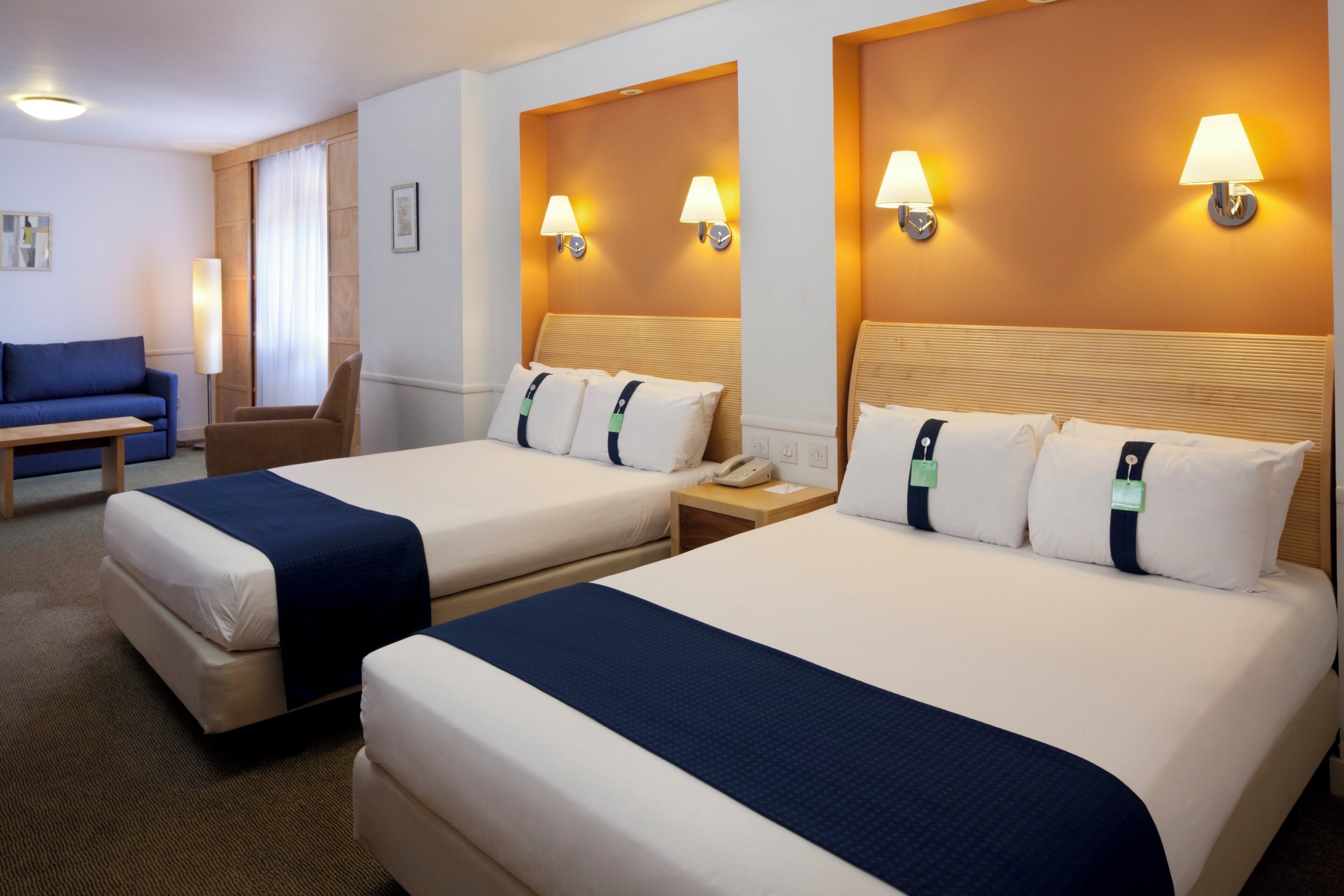 Une chambre d’hôtel avec deux lits, un bureau, une chaise et un canapé.