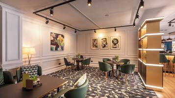 A modern hotel lobby with a central seating area, tables, chairs, and artwork on the walls.