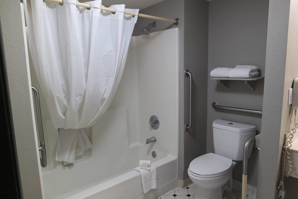 A bathroom with a bathtub, toilet, and a shelf with towels.