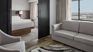 A hotel room with a bed, a sofa, a chair, a desk, and a window with a city view. - Delta Hotels by Marriott Toronto Markham (Markham)