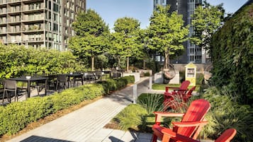 Un jardin sur le toit, doté d’un espace extérieur aménagé avec des sièges, d’un sentier et offrant une vue sur les bâtiments environnants.
