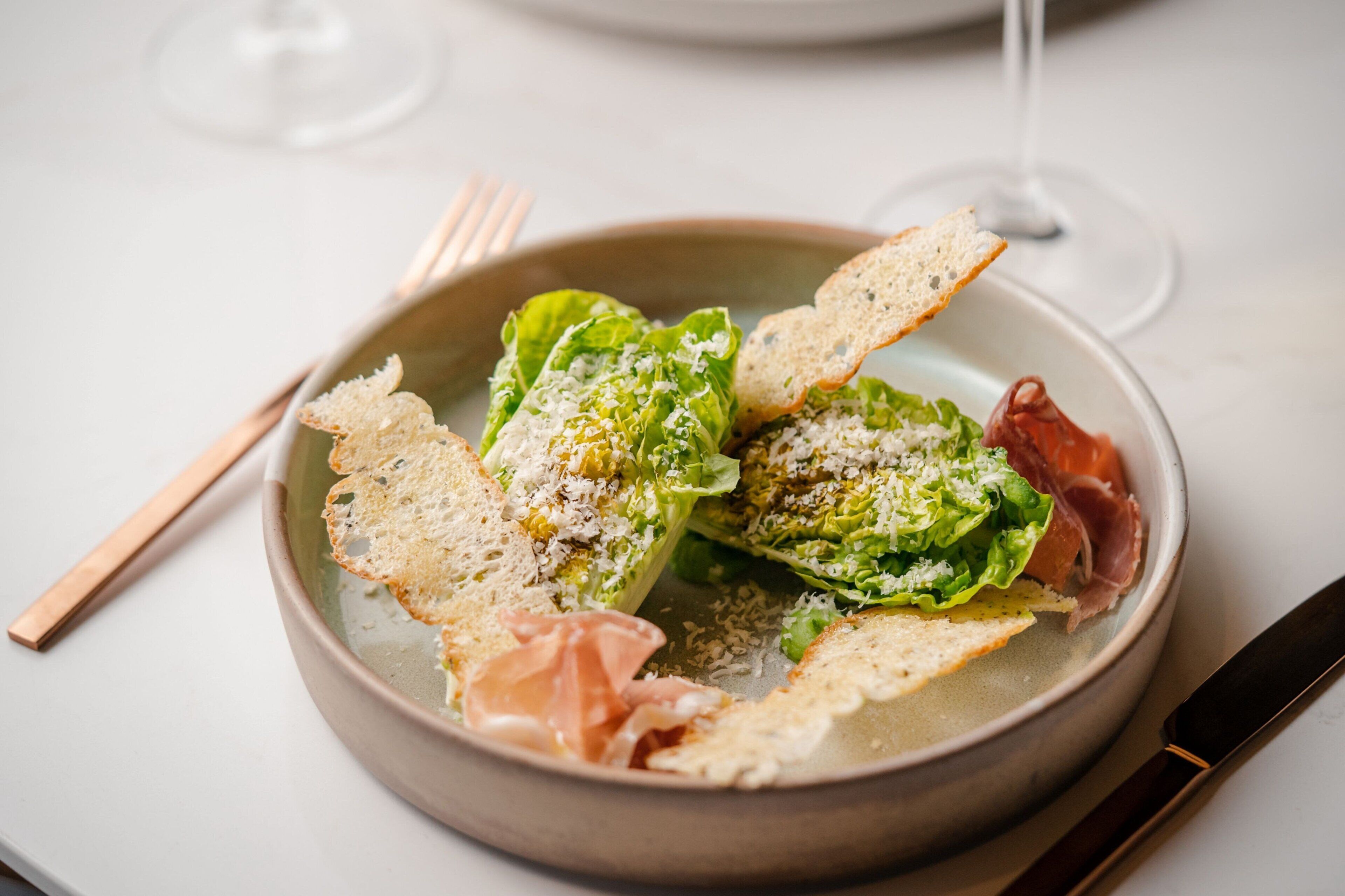 Ensalada con crutones y prosciutto en un plato.