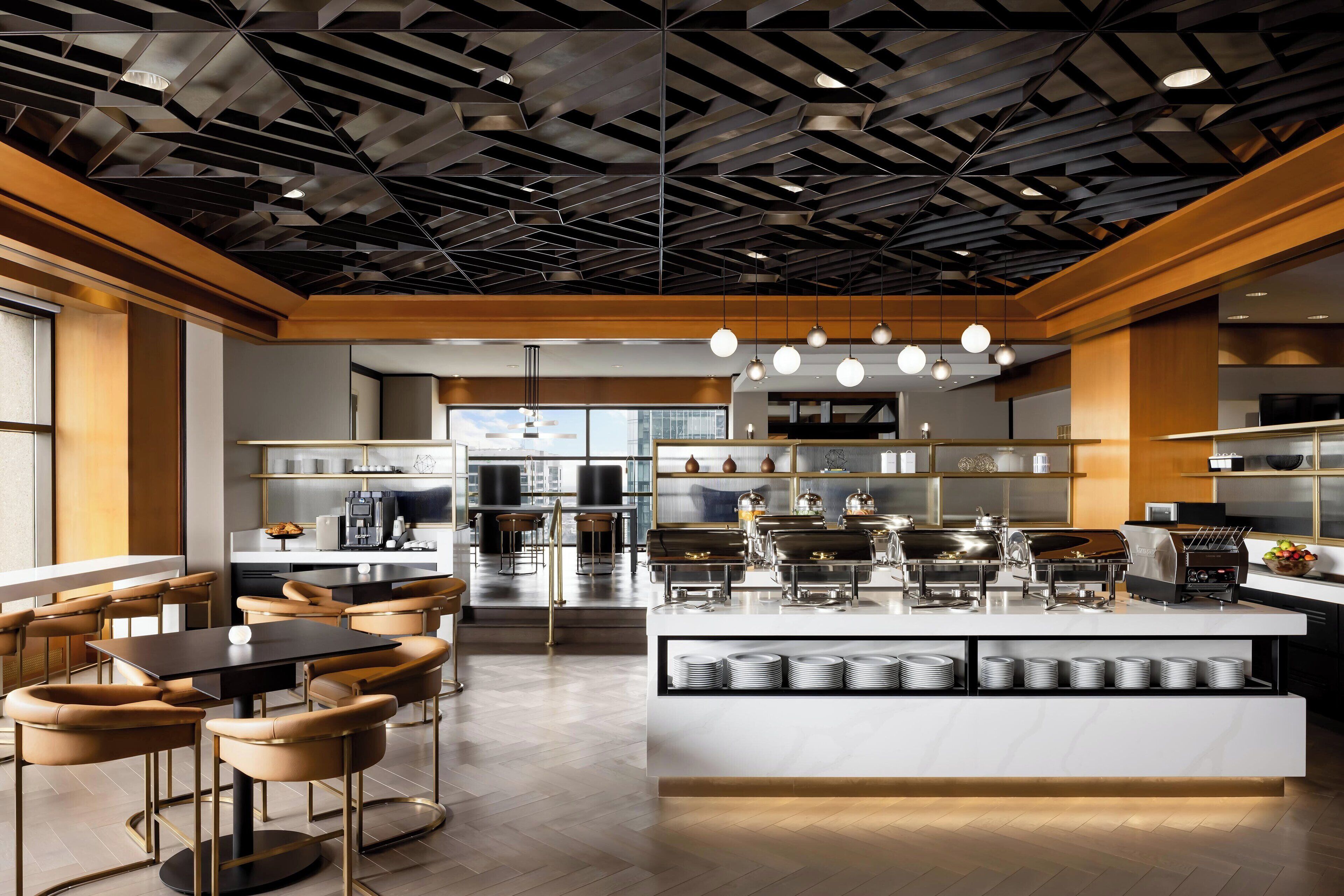 A modern kitchen with a central island, bar seating, and a geometric ceiling design.