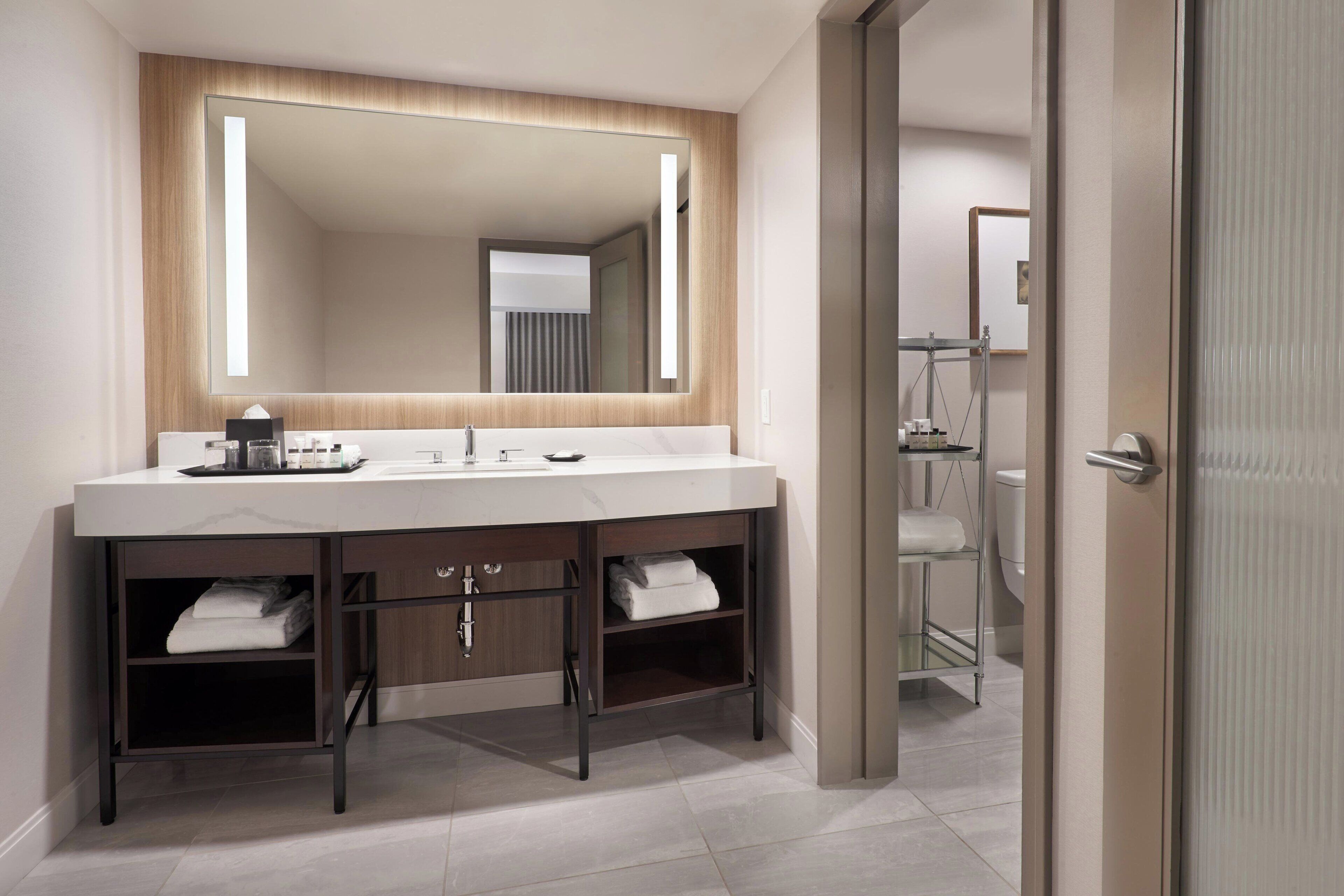 A modern bathroom with a large mirror, a white sink, and a glass shower enclosure.