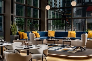 A modern interior with a blue sofa, white chairs, and a round table with glasses.
