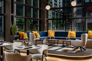 A modern interior with a blue sofa, white chairs, and a round table with glasses.
