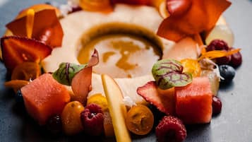 Un plato de postre con varias frutas y un hilo de caramelo.