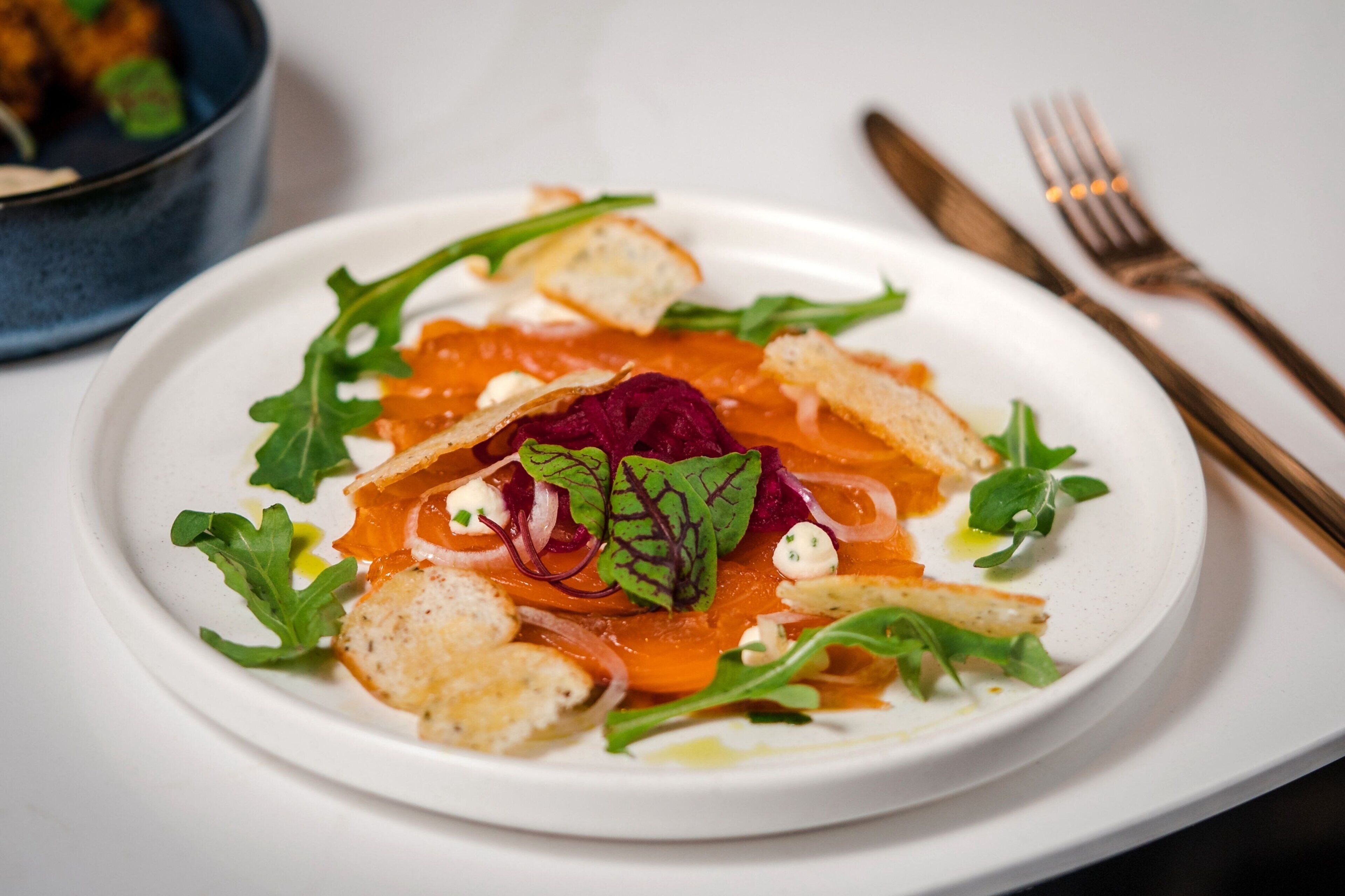 A plate of food with various garnishes and a fork and knife on the side.