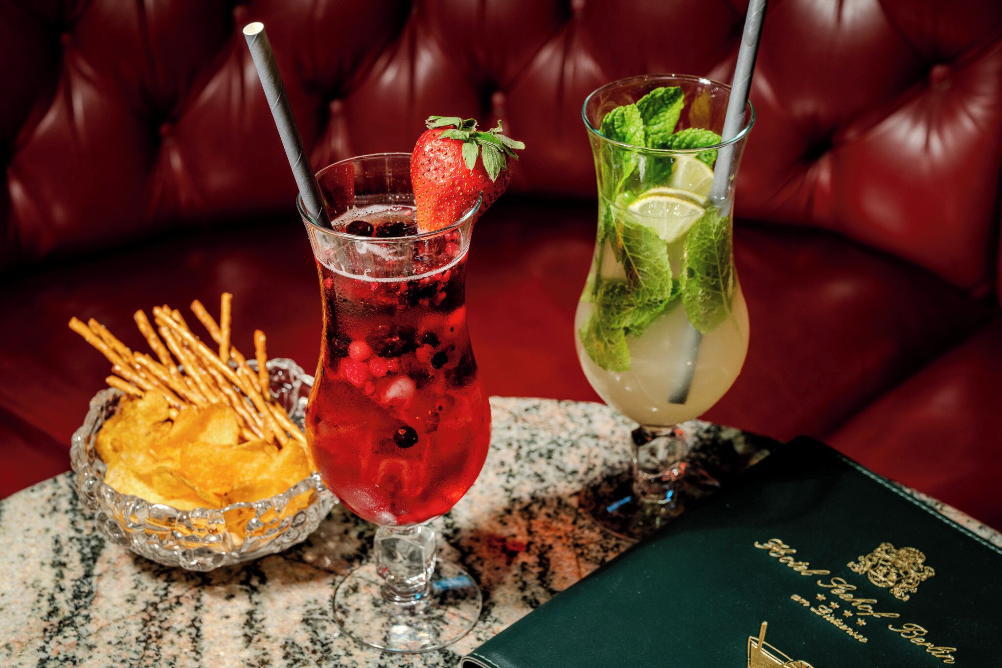 Two cocktails on a table with a leather couch in the background.