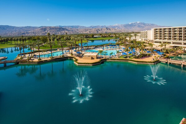 Un resort con varias piscinas, un edificio grande y montañas al fondo.