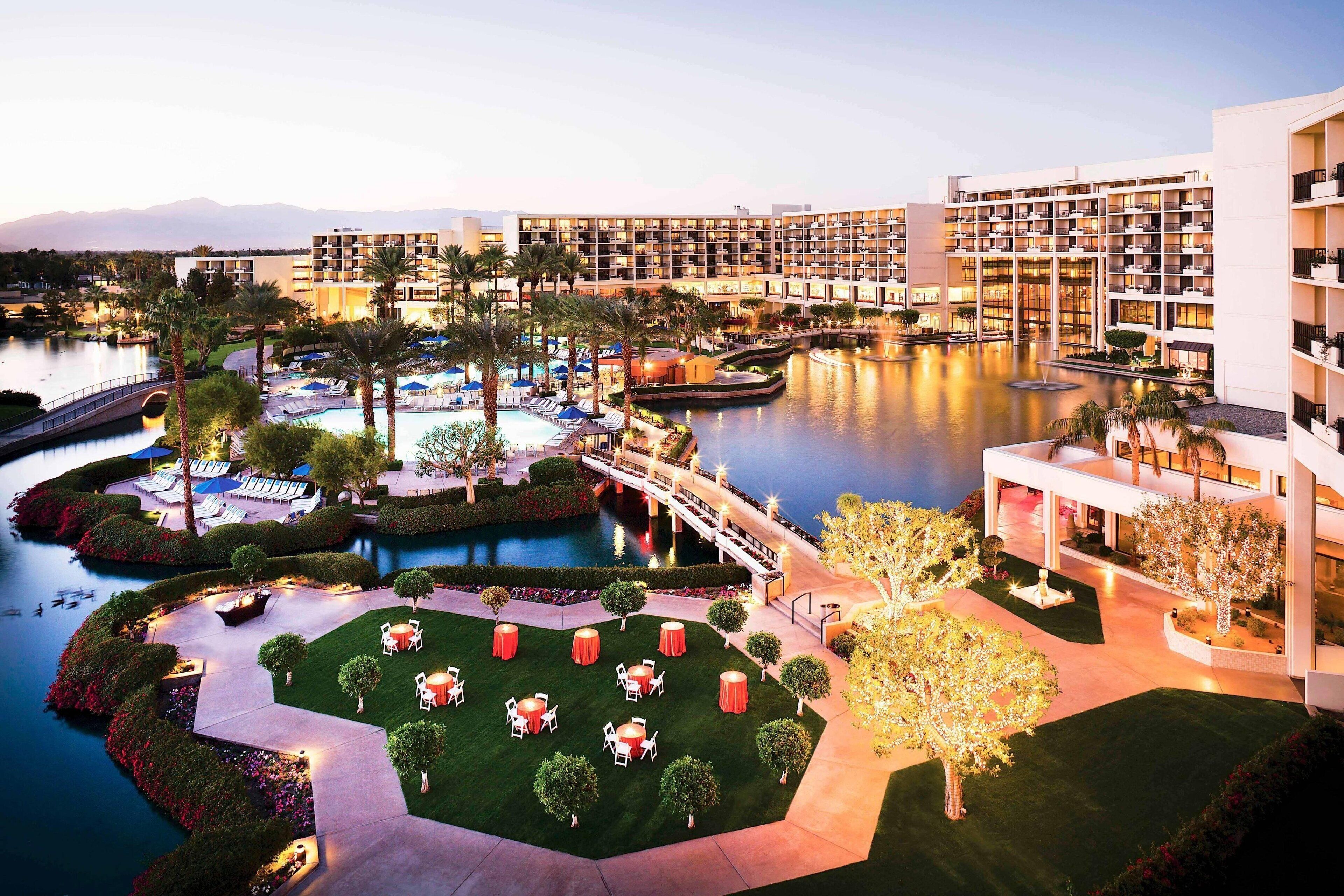 A hotel with multiple buildings, a central courtyard with a pool, and a bridge connecting different sections.