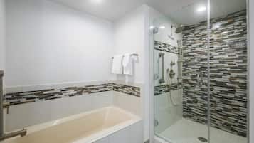 Um banheiro moderno com chuveiro envidraçado, banheira e área de banho revestida em azulejo.