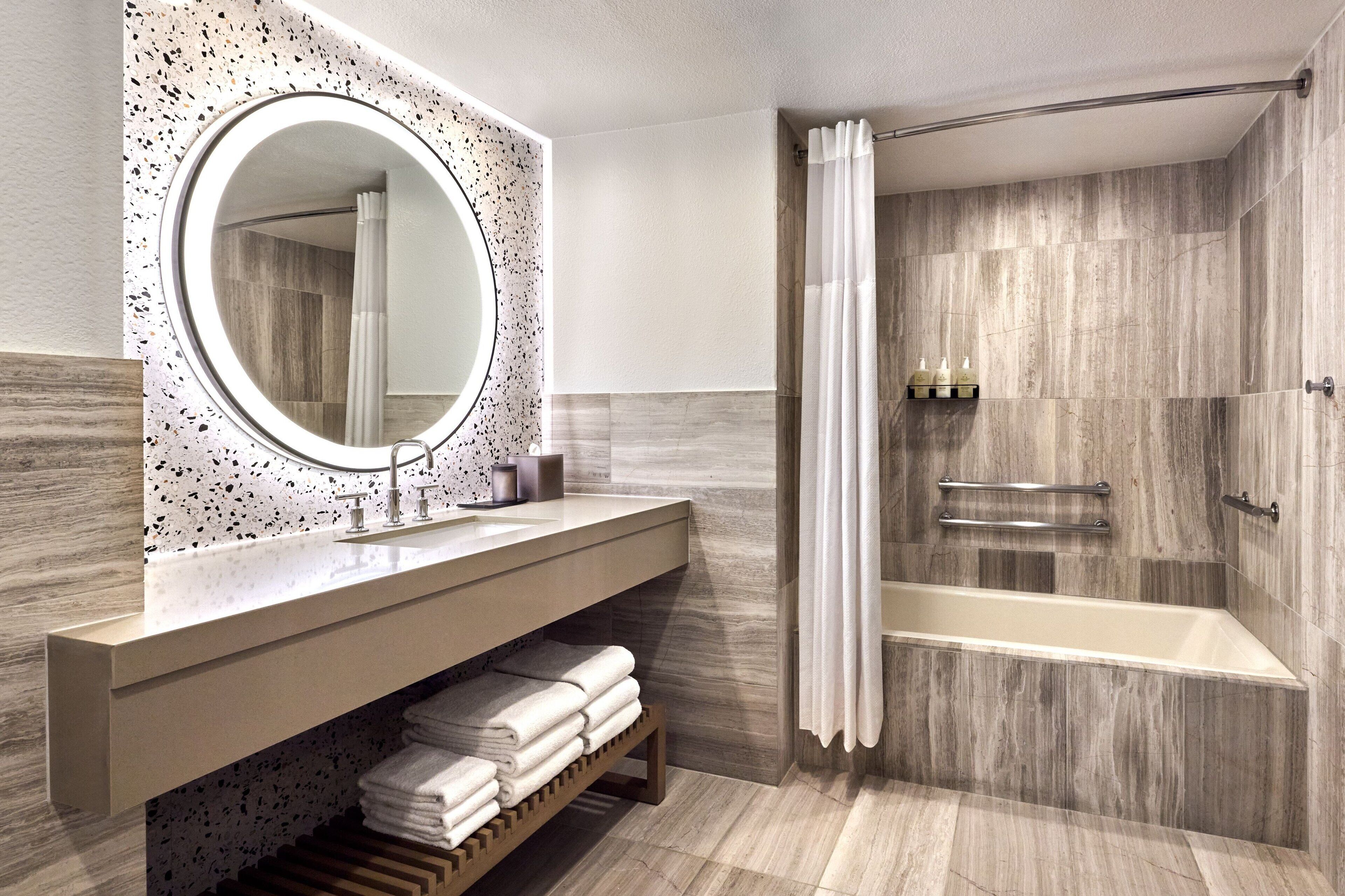 A modern bathroom with a freestanding bathtub, a vanity with a large mirror, and a towel rack.