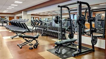 A gym with treadmills, weight benches, dumbbells, and a squat rack.