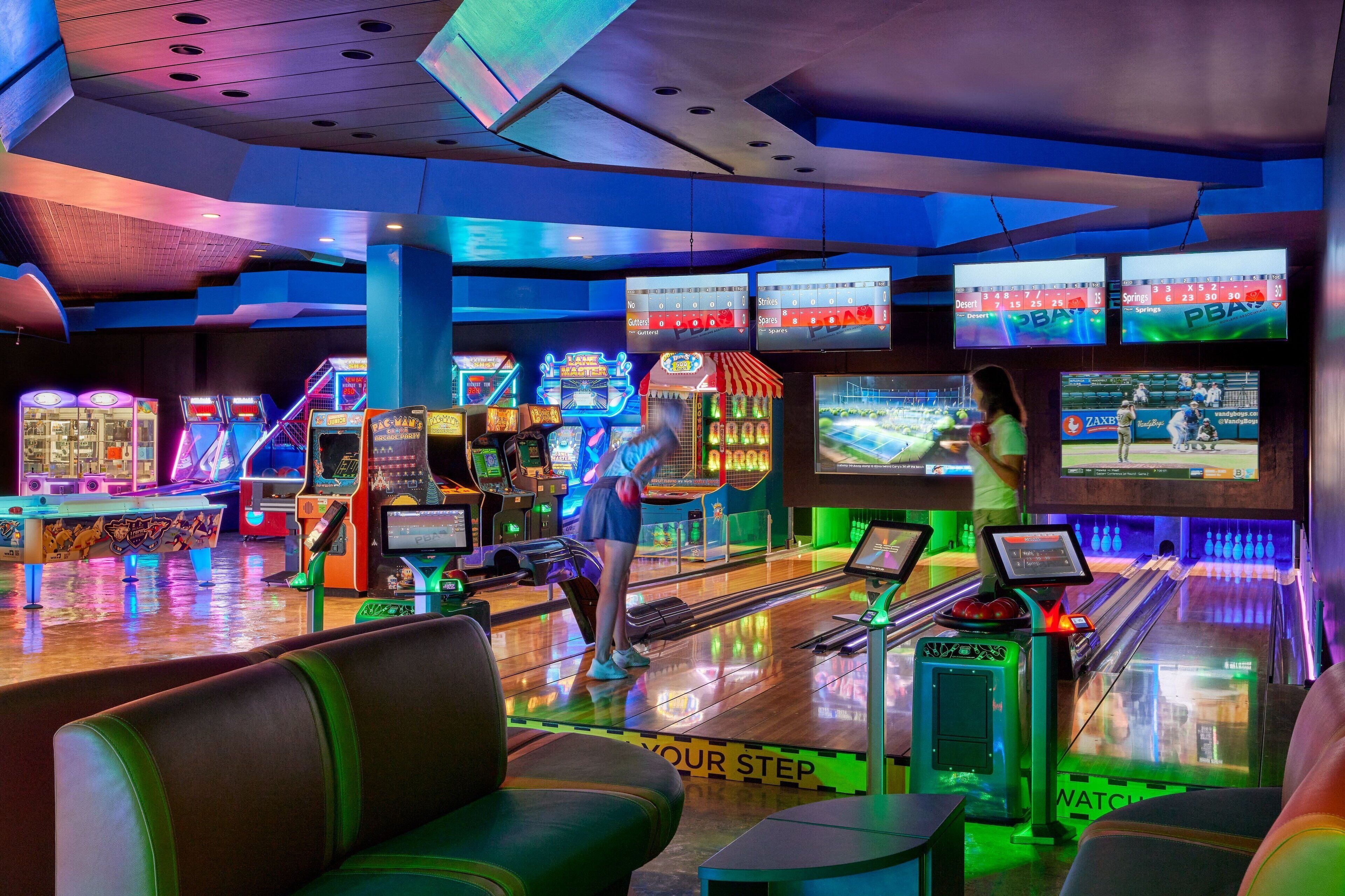A bowling alley with multiple lanes, neon lights, and arcade games.