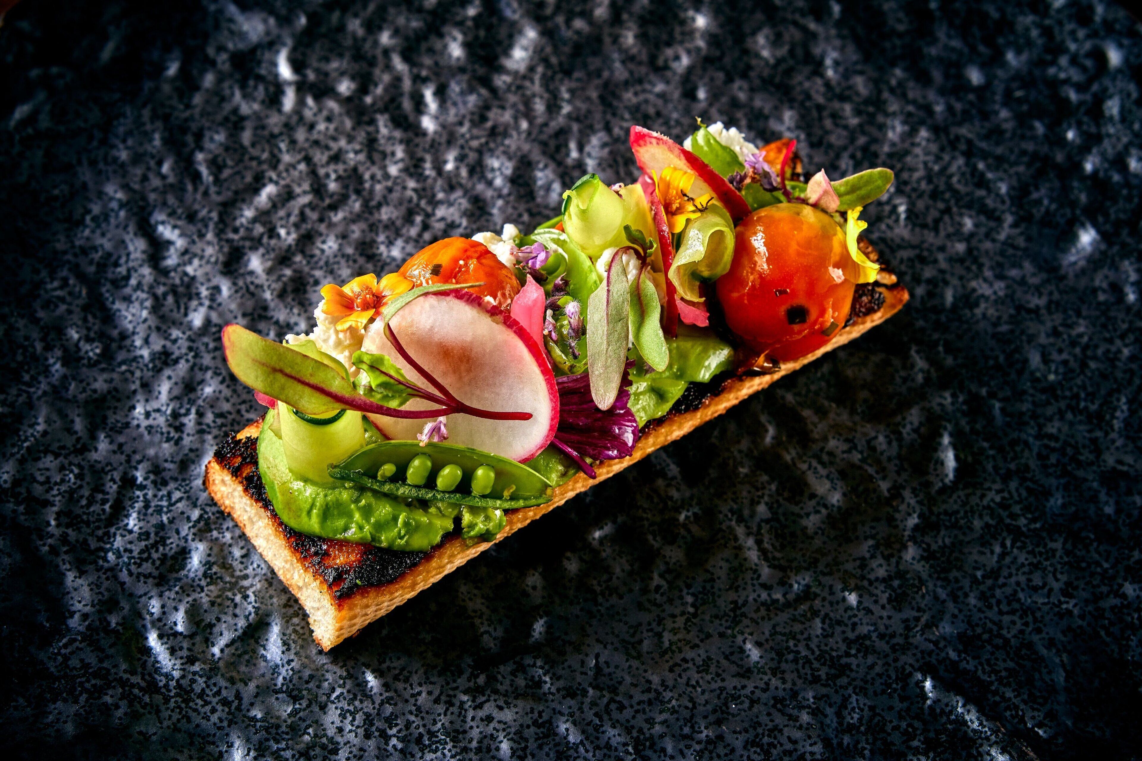 A sandwich with various vegetables on a slice of bread.