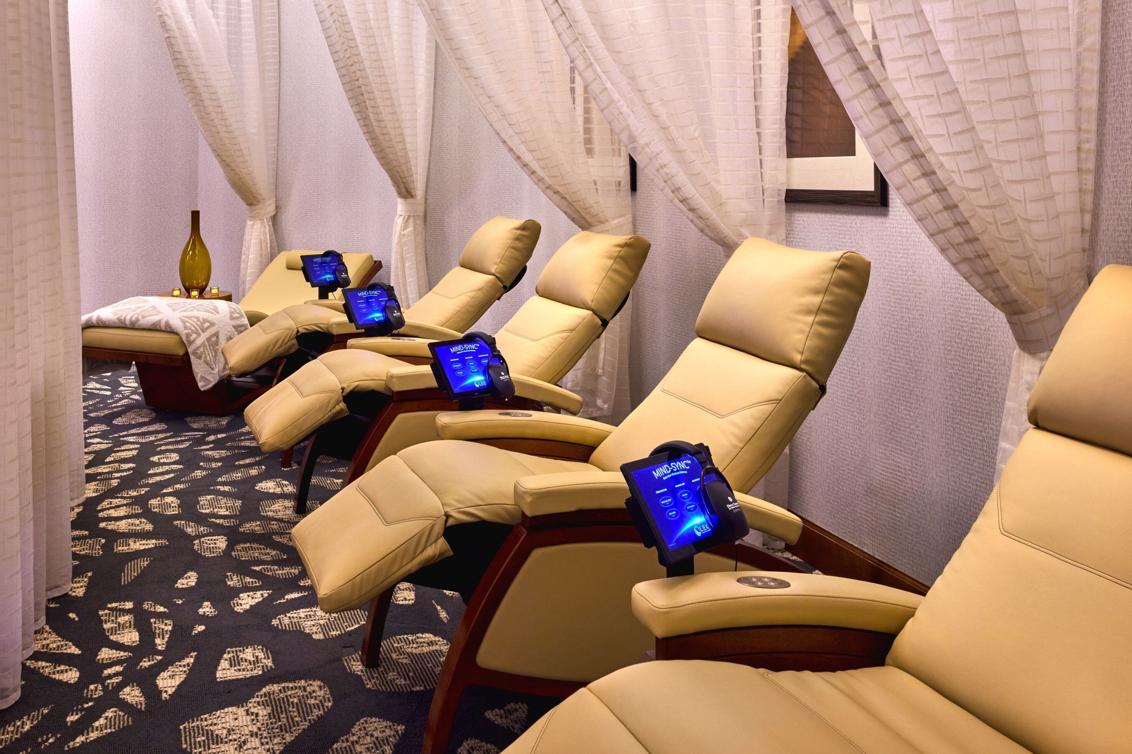 Una habitación con sillones de masaje equipados con controles digitales, alfombra estampada y un jarrón decorativo.