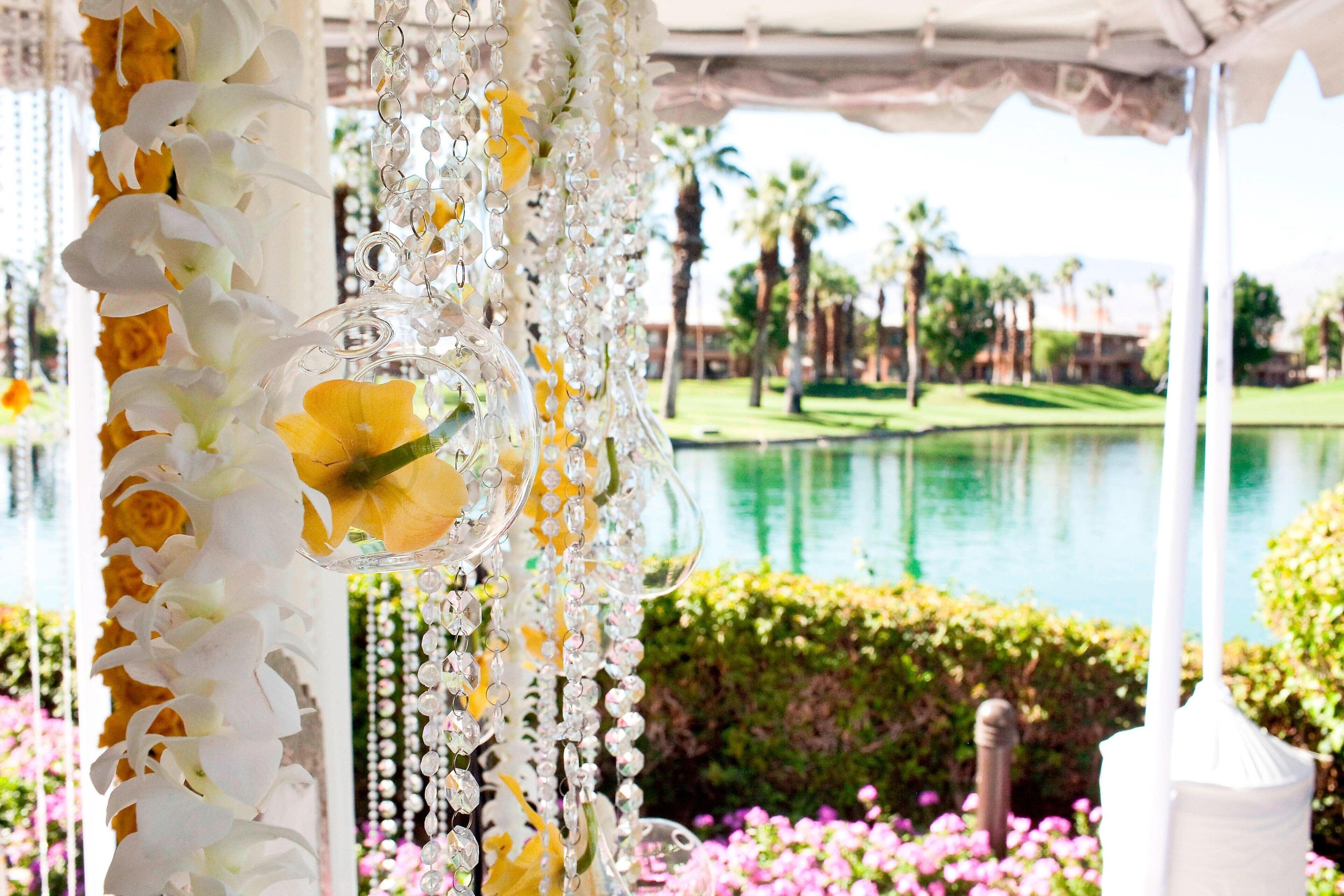 A covered outdoor area with a decorative floral arrangement and a view of a golf course and water body.