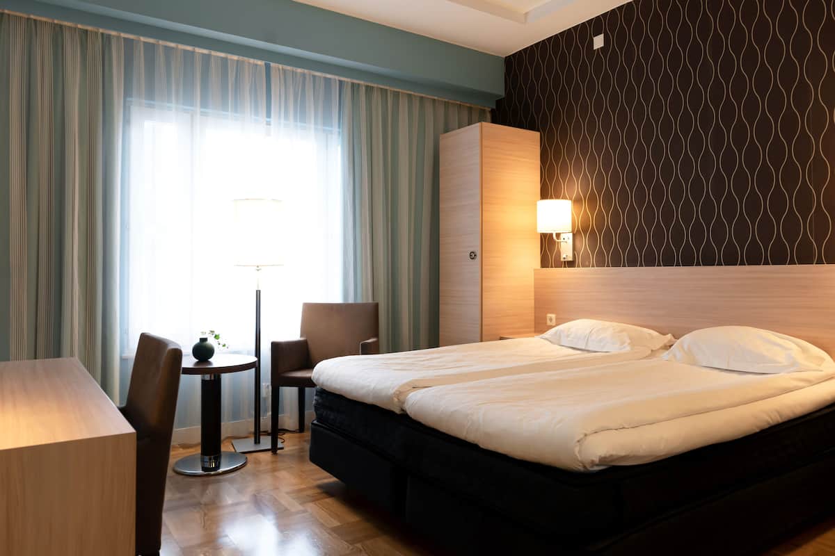 Een hotelkamer met een bed, een bureau, een stoel en een lamp.