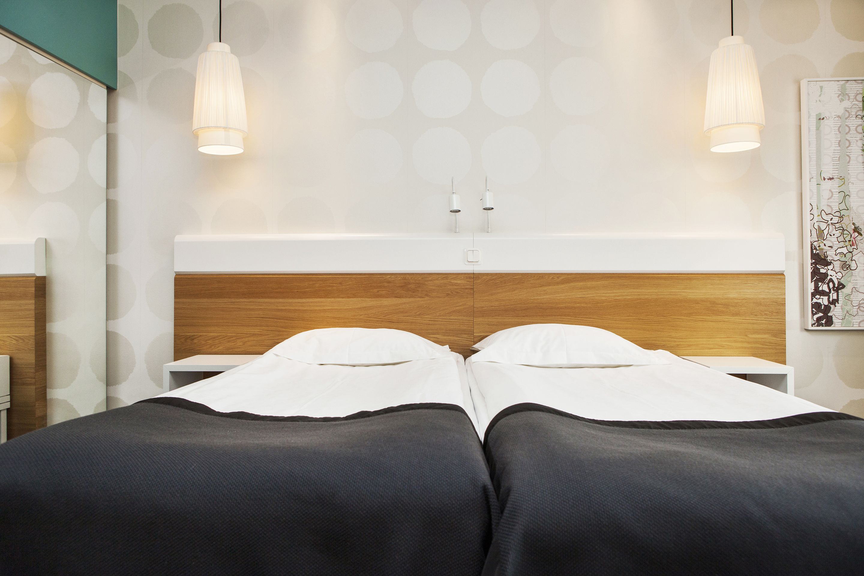 Un lit double avec une tête de lit en bois, deux tables de chevet et un mur orné de motifs circulaires.