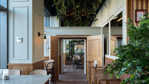 Een interieur met een visgraatvloer, houten meubels en hangplanten.