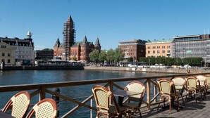 Een eetgedeelte aan de rivier met terras, uitzicht op historische gebouwen en een brug op de achtergrond.