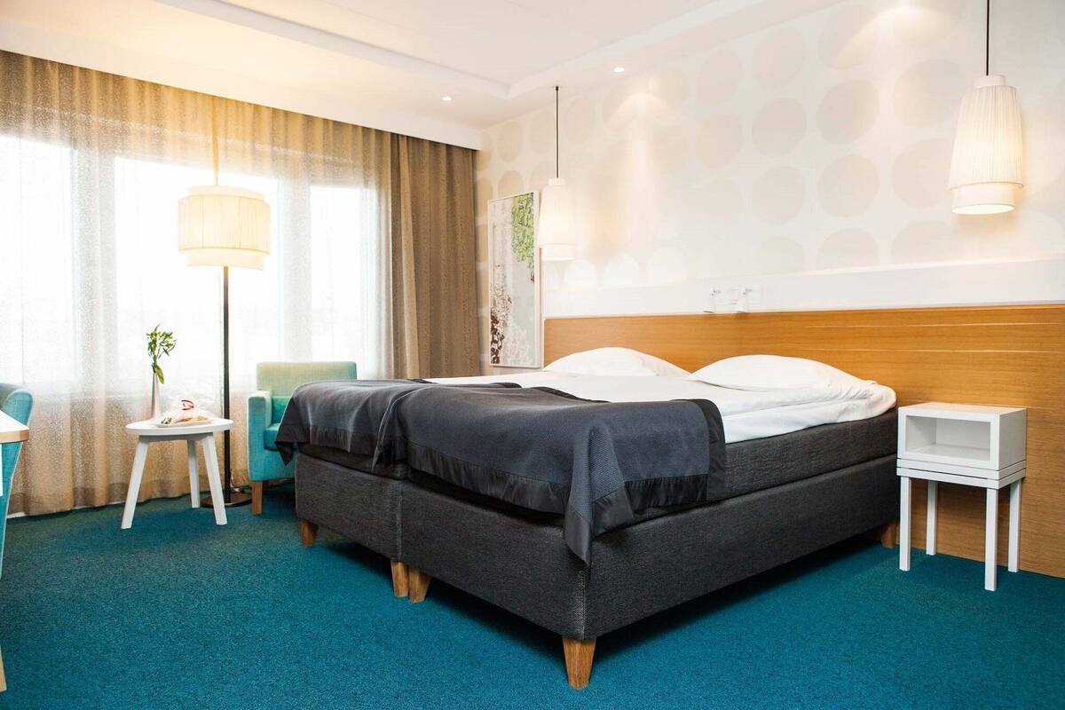 Een hotelkamer met een groot bed, een nachtkastje, een lamp en uitzicht op het omliggende landschap.