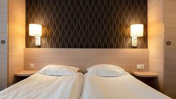 Habitación de hotel con dos camas, un papel tapiz oscuro con diseño y dos lámparas de noche.