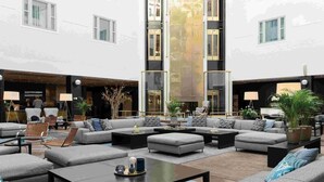 Een ruim buitengebied met meerdere banken en stoelen, een centrale salontafel en potplanten.