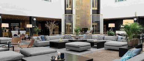 A spacious outdoor seating area with multiple sofas and chairs, a central coffee table, and potted plants.