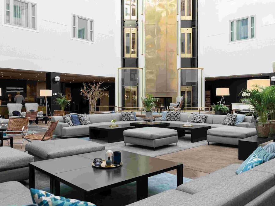 Un amplio espacio al aire libre con varios sofás y sillones, una mesa de centro y plantas en macetas.