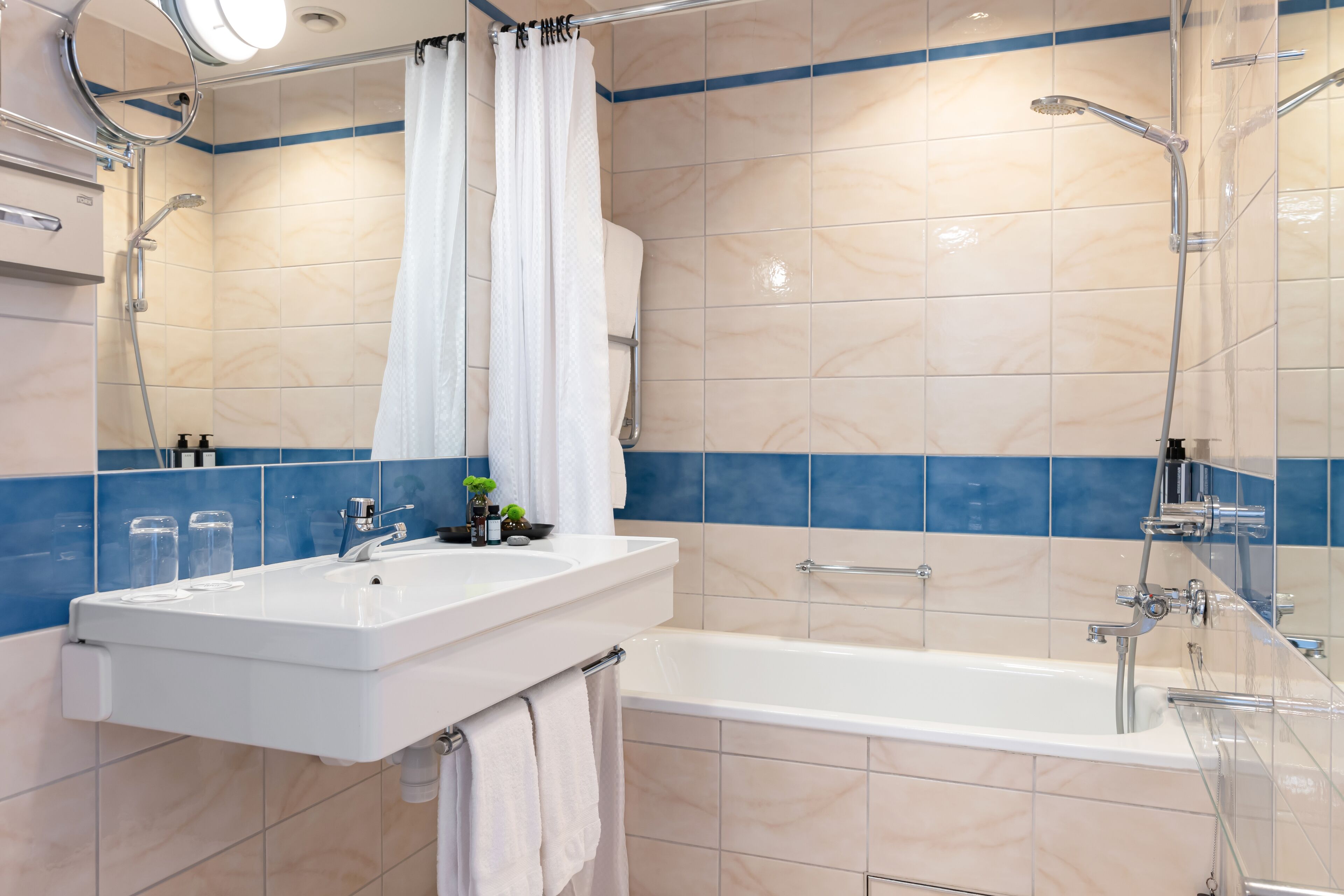 A modern bathroom with a white sink, a bathtub, and a shower area.