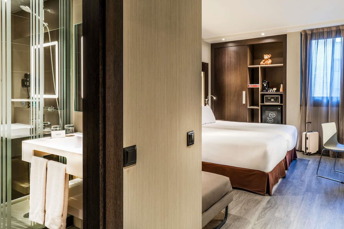 Ein Hotelzimmer mit Bett, Schreibtisch, Stuhl, Kleiderschrank und einem Badezimmer mit Dusche.
