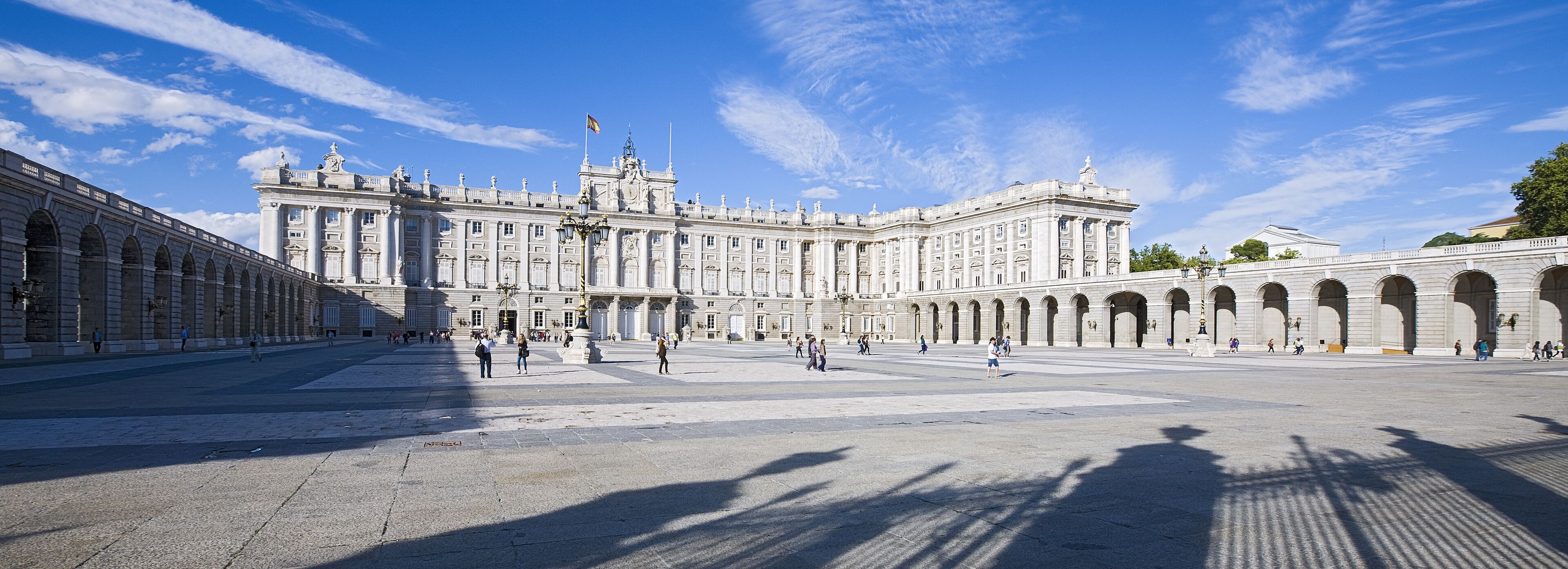 A large, historic building with classical architecture, featuring a central courtyard and multiple arches.